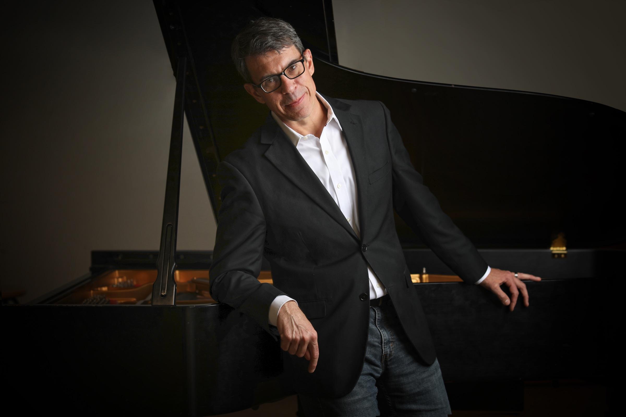 David DeMotta leaning against a grand piano